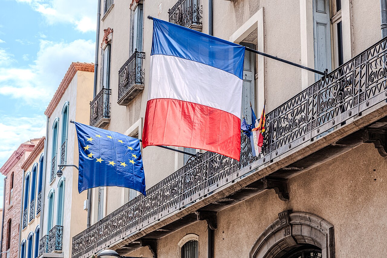 Drapeau français tricolore et drapeau de l'Union européenne côte à côte, symbole de la double appartenance du citoyen naturalisé français et européen